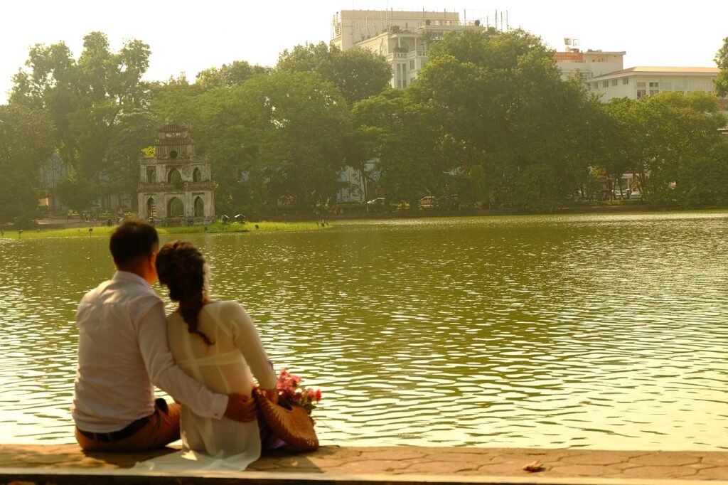 Couple assis au bord du lac Hoan Kiem à Hanoi, face à la tour de la Tortue