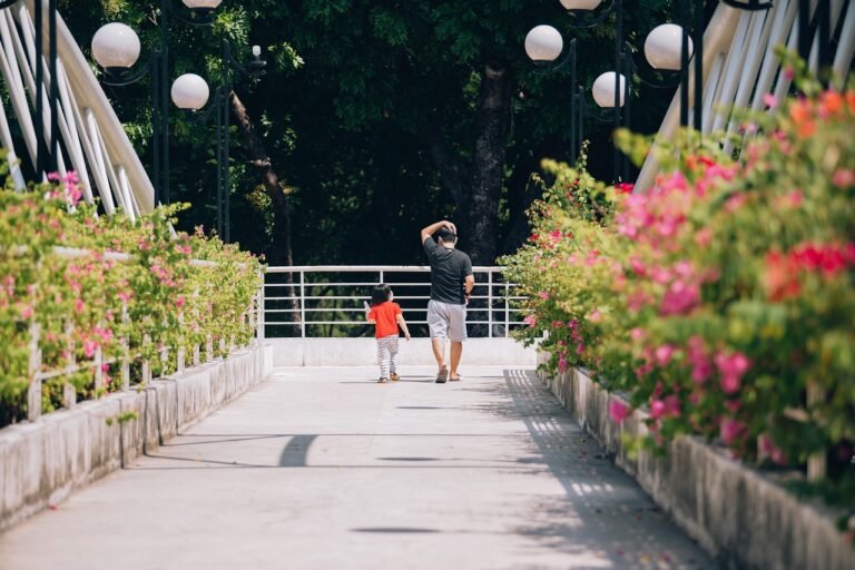 Un père et son enfant en promenade sur un pont bordé de fleurs